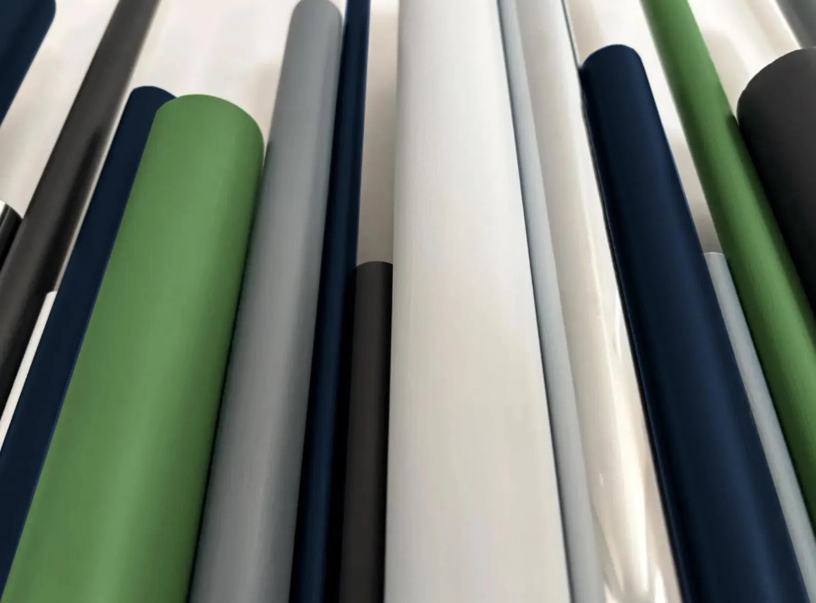A close-up view of multiple vertical wooden dowels in different colors, including white, gray, navy, green, and black.